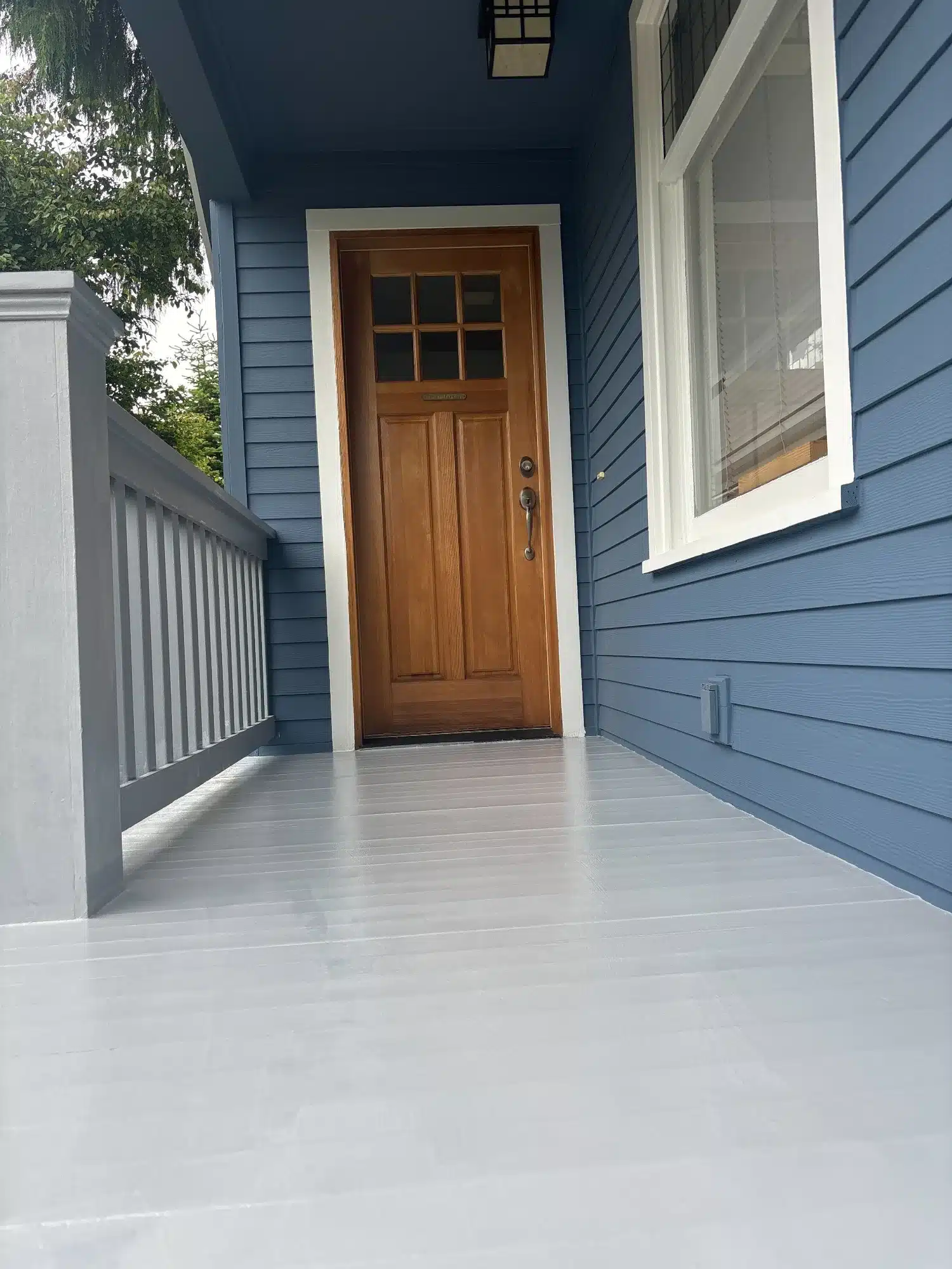 Blue Exterior Home With Wood Door Blue-painted residential exterior entryway with wood entry door, white trim, and light gray deck flooring in Seattle, WA